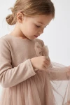 Beige festkjole Iga – tylsløjfe på brystet og overdel i jersey med lange ærmer, nærbillede fra siden