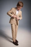 Beige jakkesæt til drenge Liam – blazer og bukser, drengen knapper blazeren, set forfra